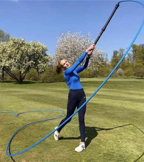 A woman using the Mach 3 SpeedBomber golf training tool.