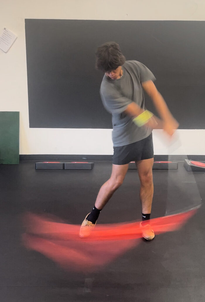 A man demonstrating the Mach 3 Iron Whip golf speed training tool.