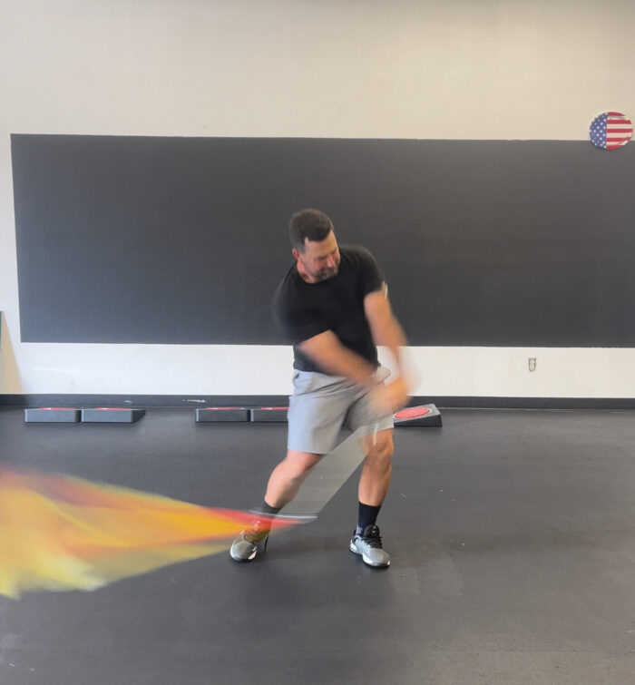 A man demonstrating the Mach 3 Iron Whip golf speed training tool.