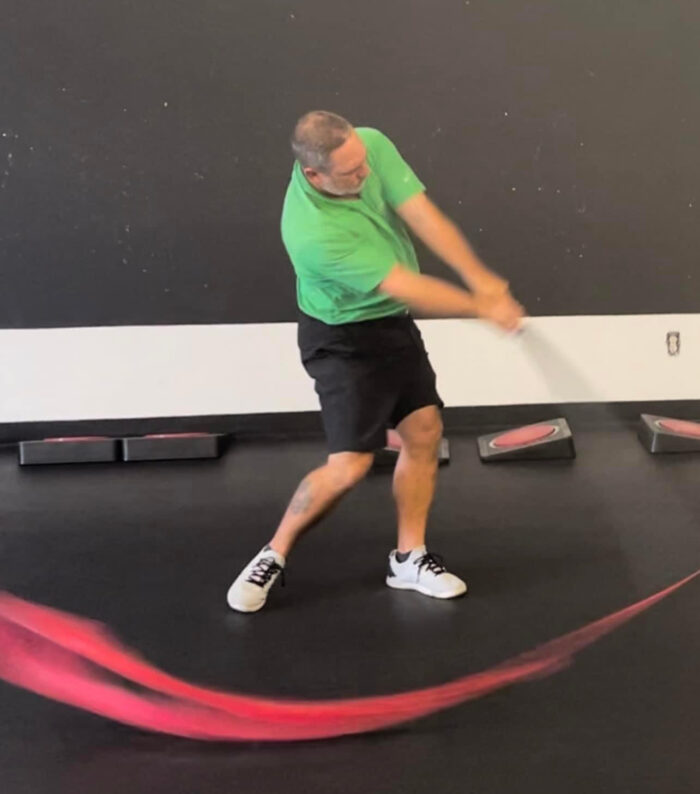 A man demonstrating the Mach 3 Iron Whip golf speed training tool.