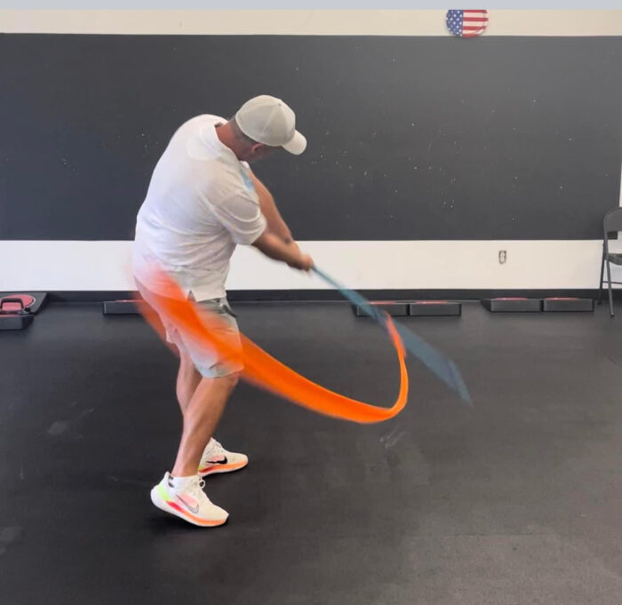 A man demonstrating the Mach 3 Iron Whip golf speed training tool.