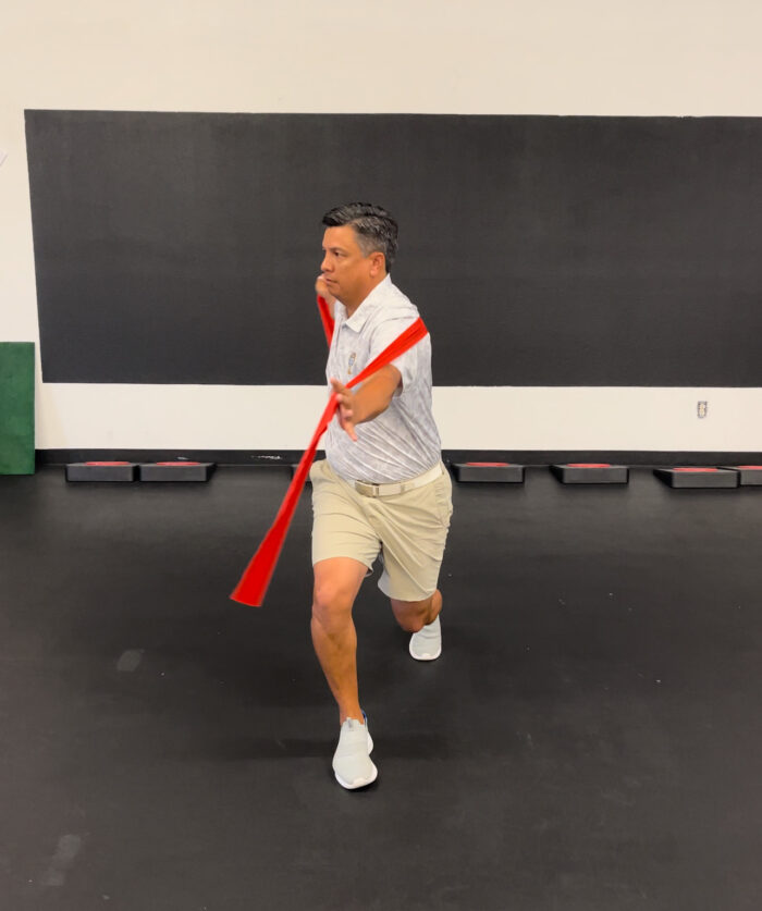 A man demonstrating the Mach 3 Iron Whip golf speed training tool.